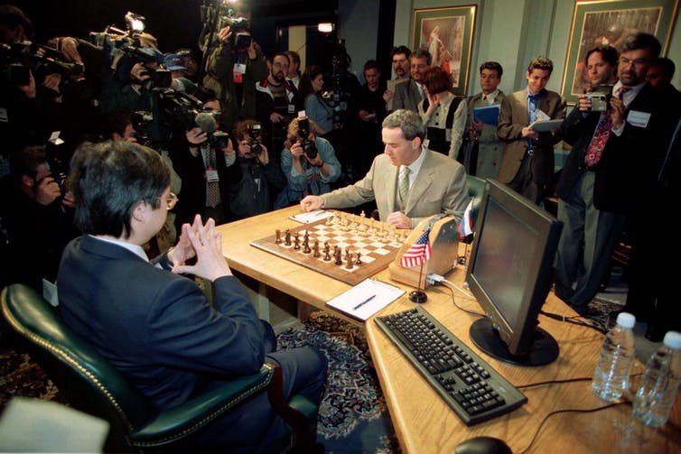 World chess champion Gary Kasparov at the 1997 rematch against IBM's Deep Blue supercomputer.  Moving the pieces for the machine is Feng siung-Hsu, one of Deep Blue's original developers.  The historic 6-game rematch was the first time a computer defeated a world champion under official tournament regulations.