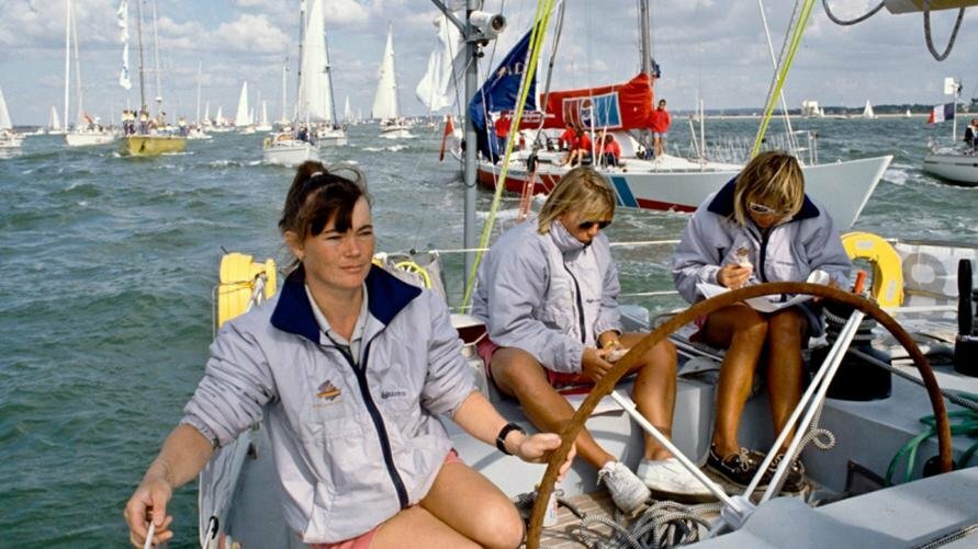 Tracy Edwards at the helm of the yacht 'Maiden' with two of her crew members behind. In 1989/90, she made history by becoming the first woman to skipper an all-female team at the Whitbread Round the World Race, earning her the Yachtsman of the Year Trophy.